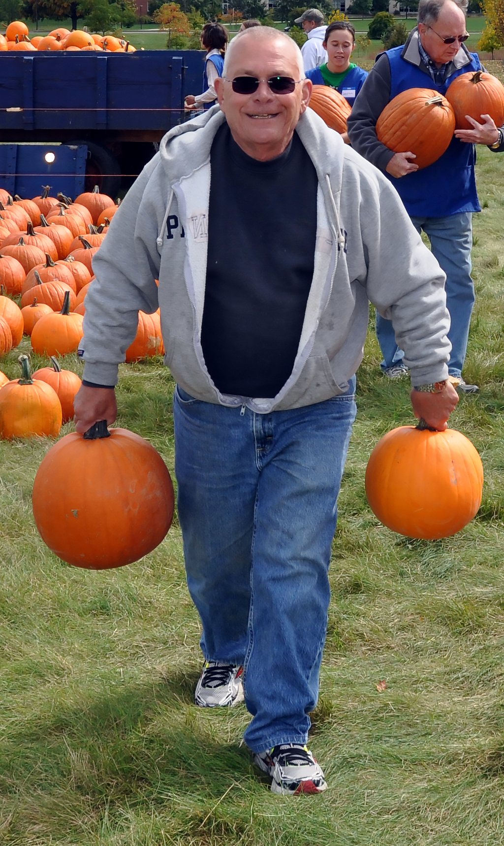 adult volunteer carries two pumpkins
