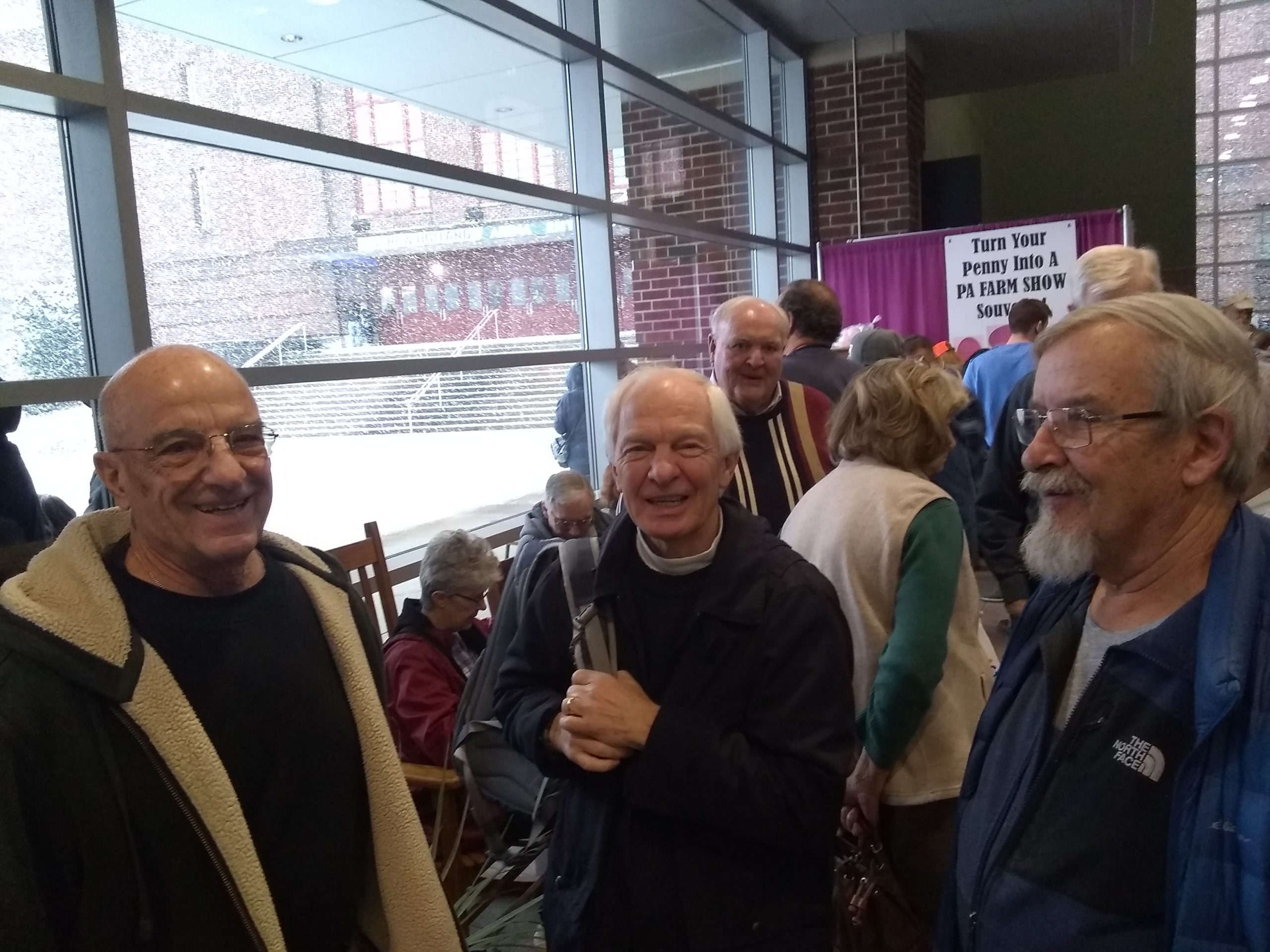 three adult men gather at indoor event