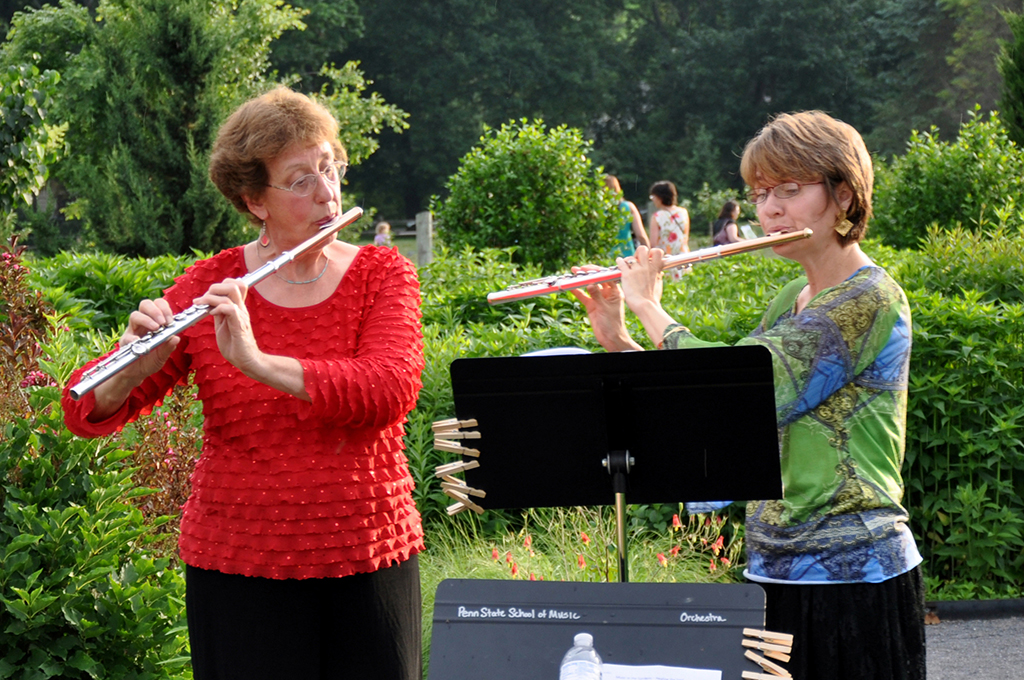 two women play flutes in a garden concert