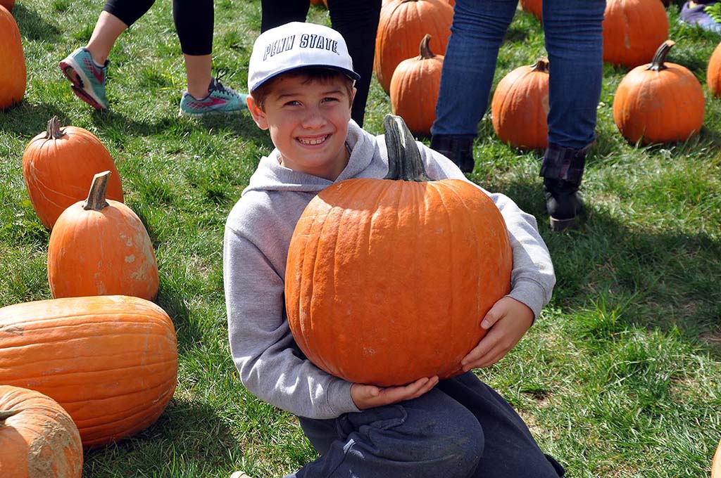 teenage boy holds a large pumpkin