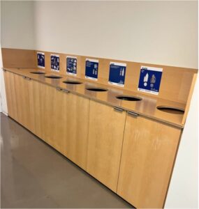 image of recycling and trash bins in a row, with signs above.
