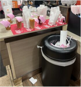 image of coffee shop trash can, almost overflowing with trash