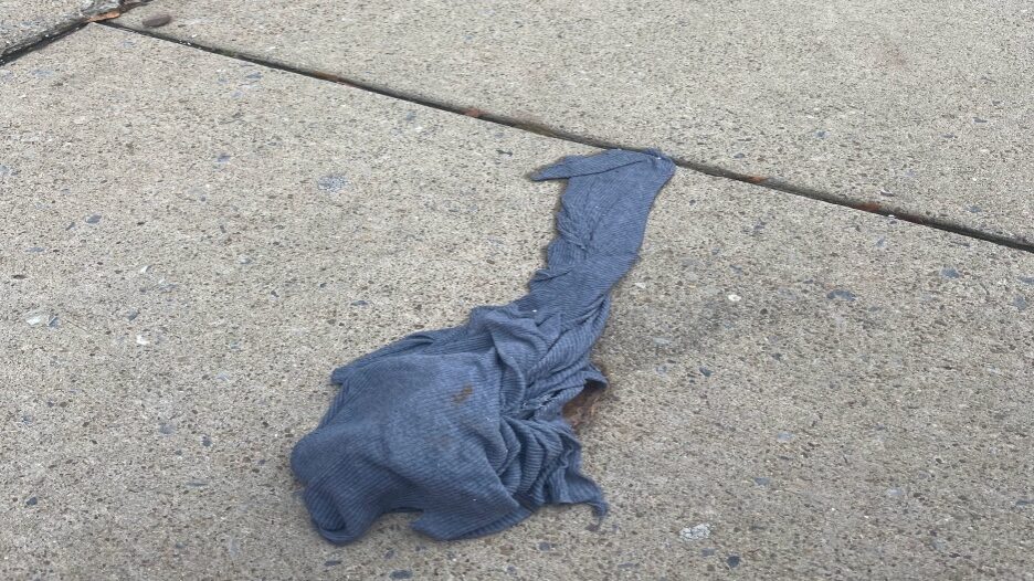 sidewalk with a piece of dirty blue laundry on it