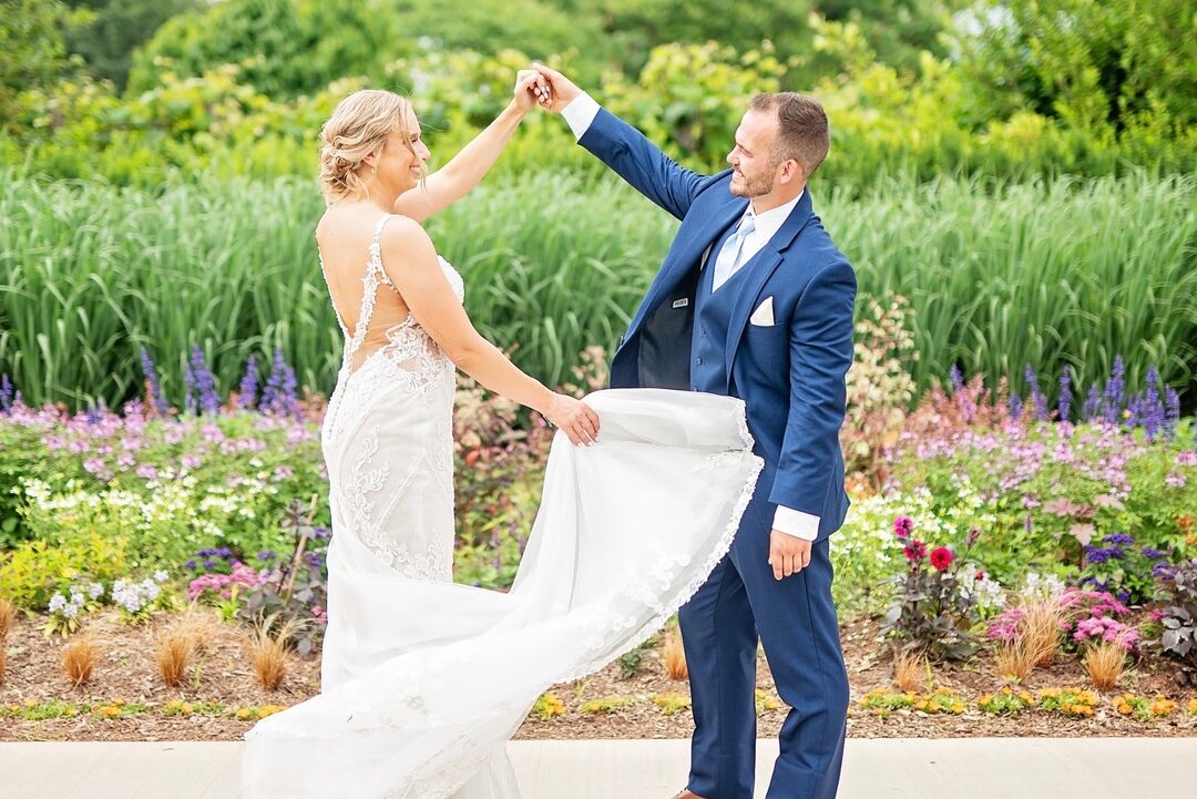 Bride and groom holding hands in front of flower garden